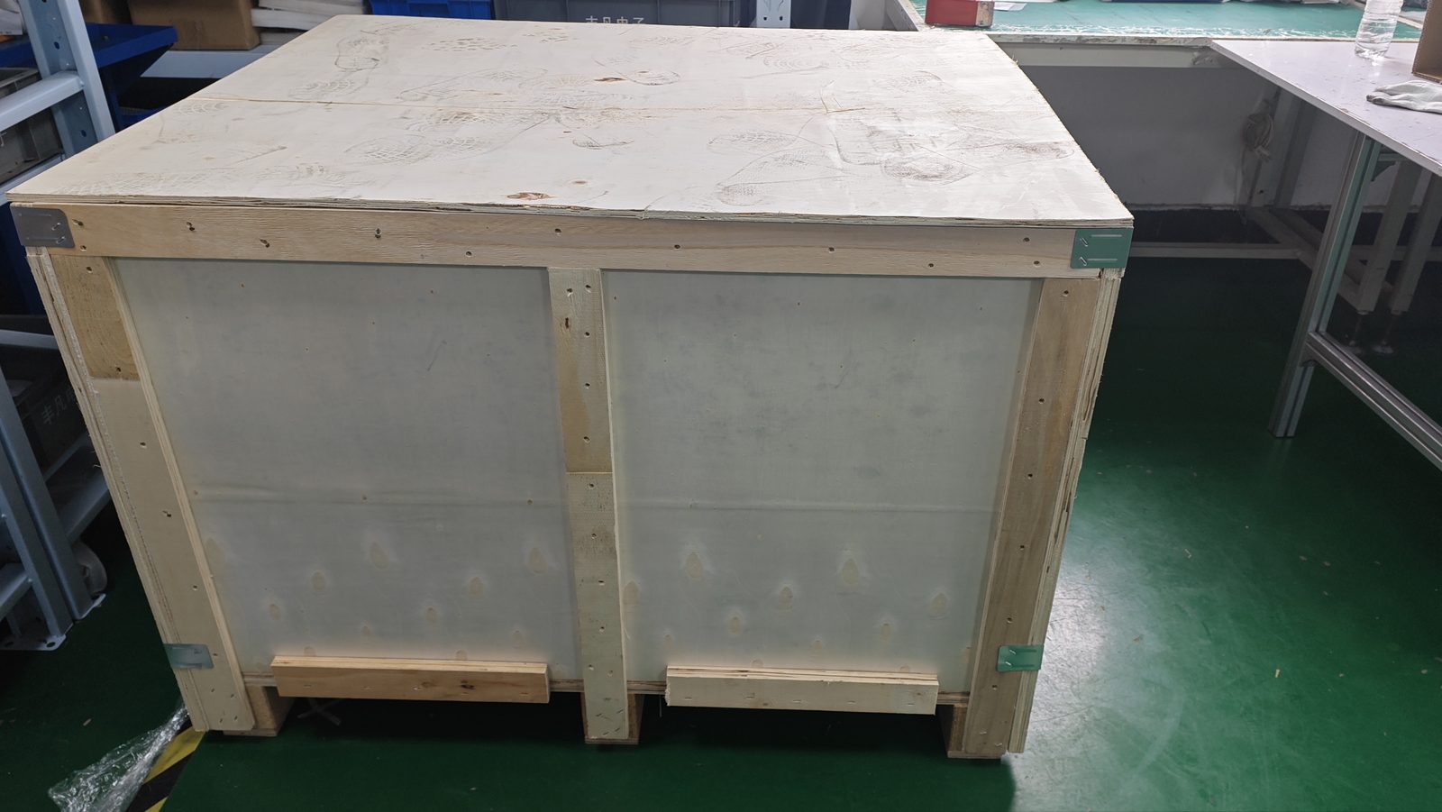 Sealed plywood export crate with reinforced steel corners and fork-lift skids on the shop floor