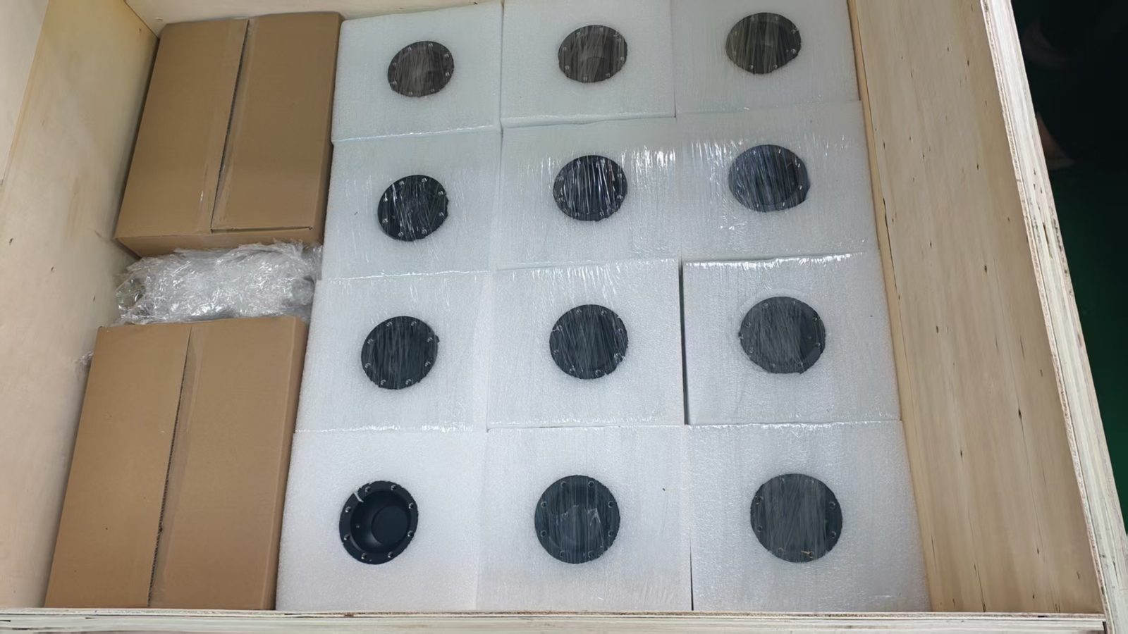 CNC parts individually foam-wrapped and bedded into a plywood crate, with boxed items packed alongside